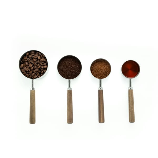 Four measuring cups with wooden handles in a row on a white table
