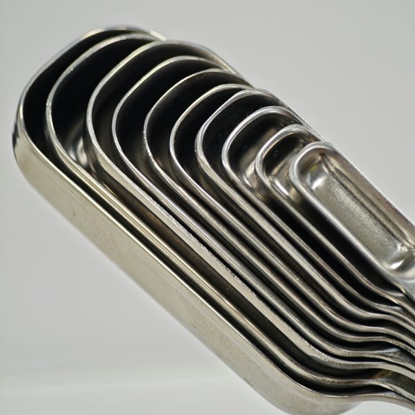 Set of stainless steel measuring spoons nested together on a white surface